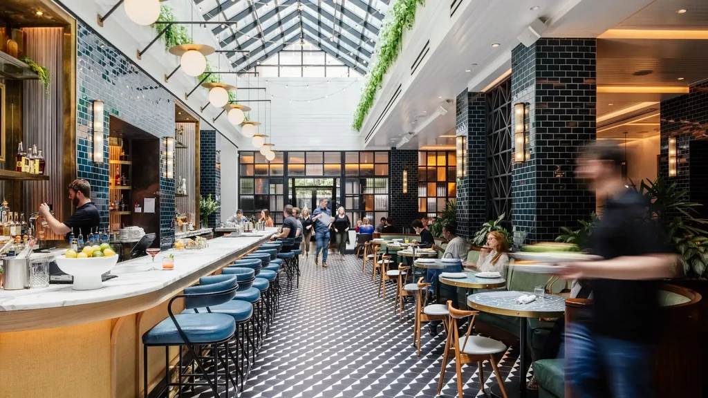 Bright, modern restaurant interior with a bar, dining, and patrons.