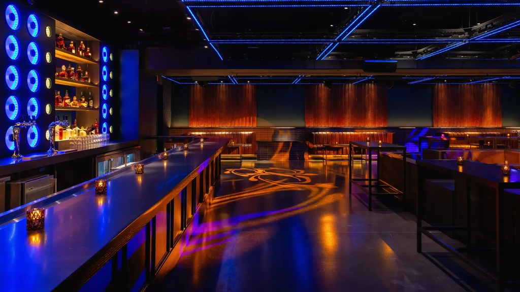 Empty modern bar with blue LEDs and amber floor projection.