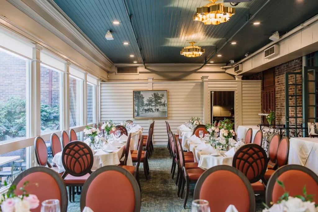 Elegant dining room with set tables, floral centerpieces, and golden chandeliers.