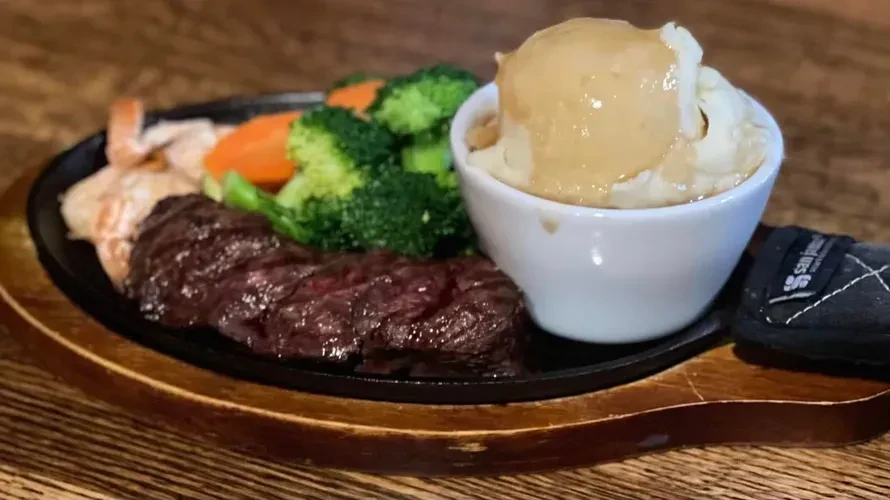 Steak and shrimp with mashed potatoes, gravy, and vegetables.