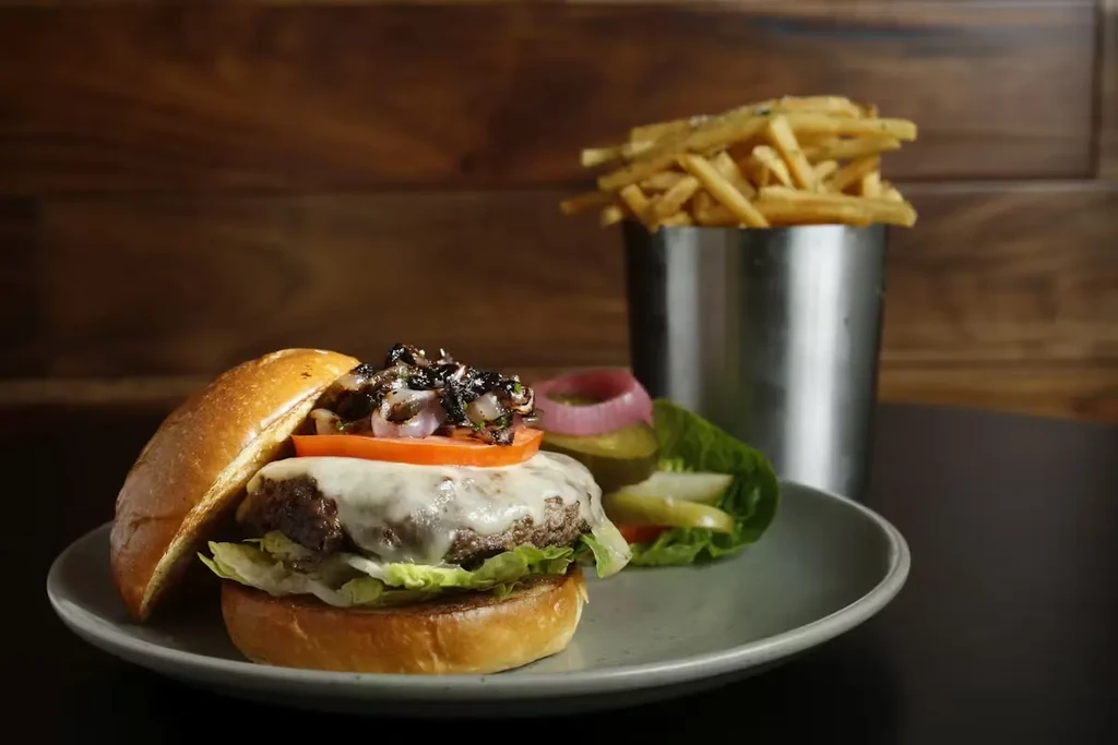 A cheeseburger with toppings, a side salad, and a cup of fries.
