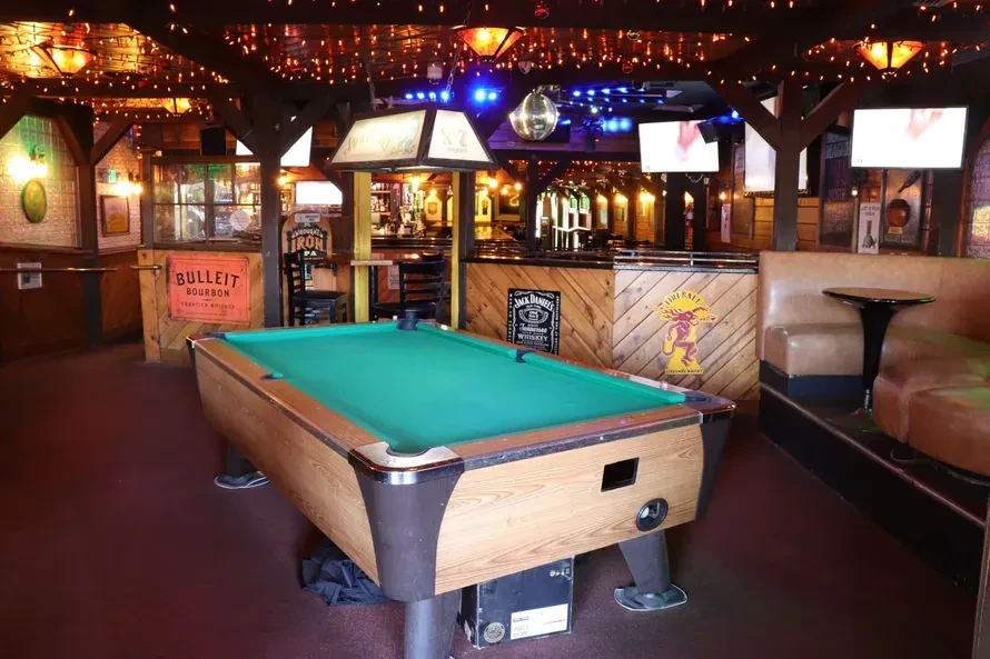 An empty bar with a pool table and string lights.