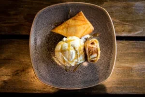 Dessert plate with a fried pastry, ice cream, and a spring roll.
