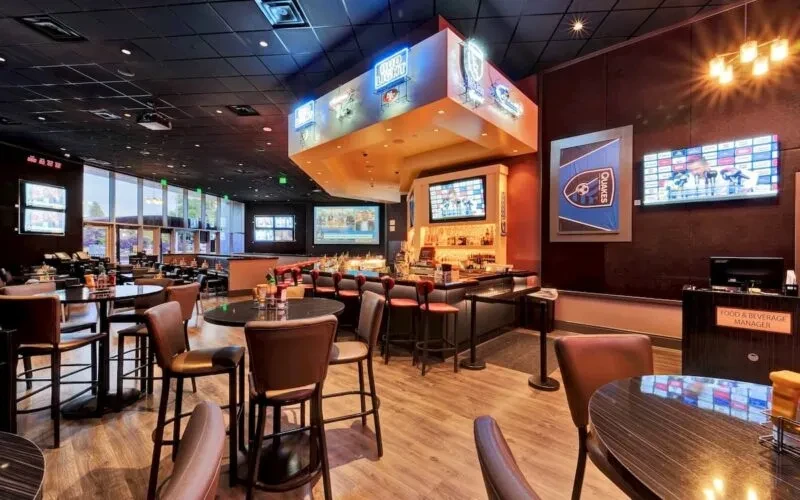 Empty bar and restaurant with high top tables and large windows.