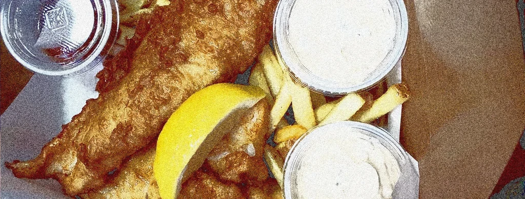 Crispy fish and chips with lemon and dipping sauces.