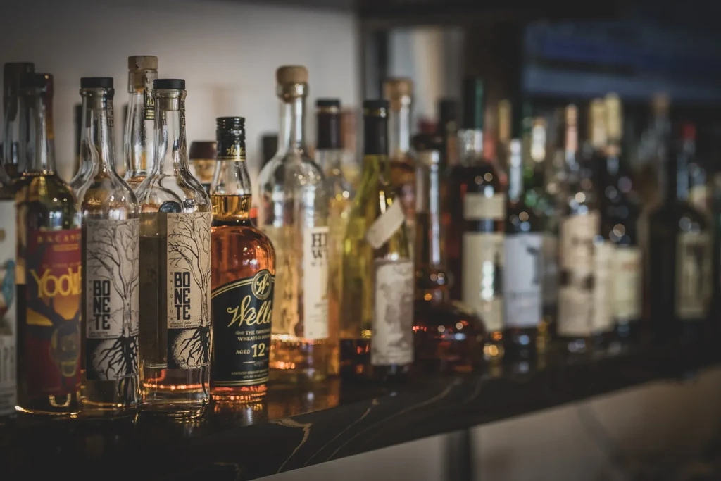 Rows of assorted liquor bottles on a dark bar shelf.