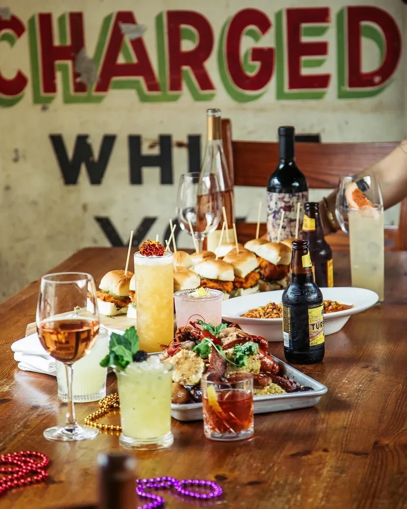A table with drinks, sliders, and a platter of seafood and corn.