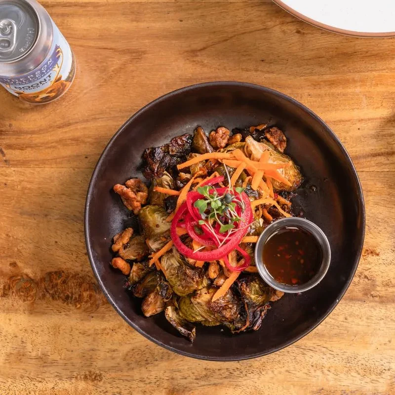 A bowl of roasted Brussels sprouts, walnuts, and shredded vegetables.