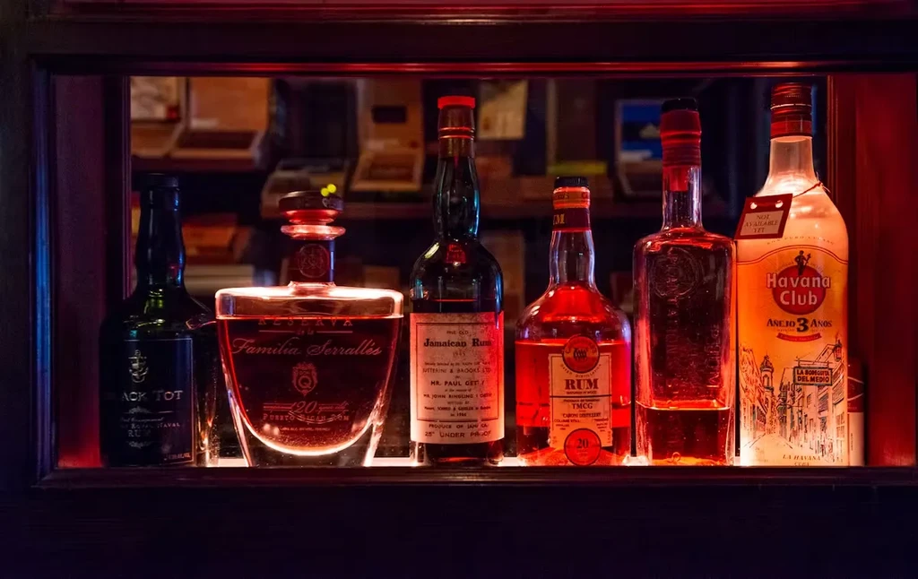 Six bottles of rum are displayed on a shelf with red backlighting.