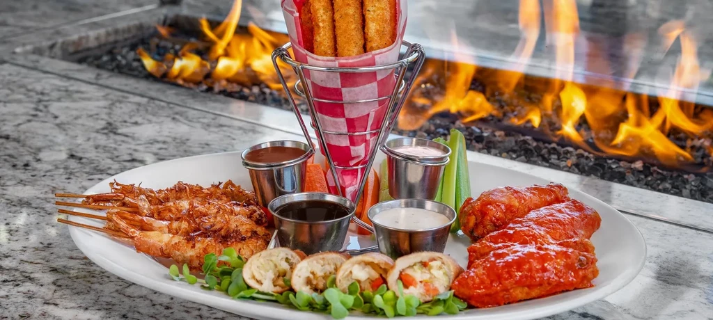 Platter of coconut shrimp, spring rolls, mozzarella sticks, and buffalo wings.