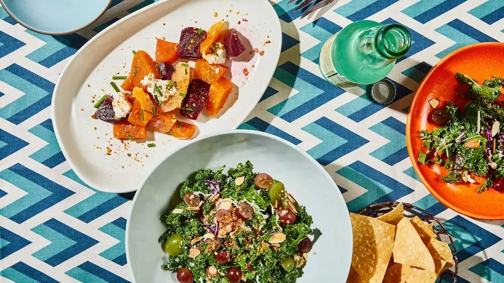 Overhead view of various dishes and a drink on a patterned tablecloth.