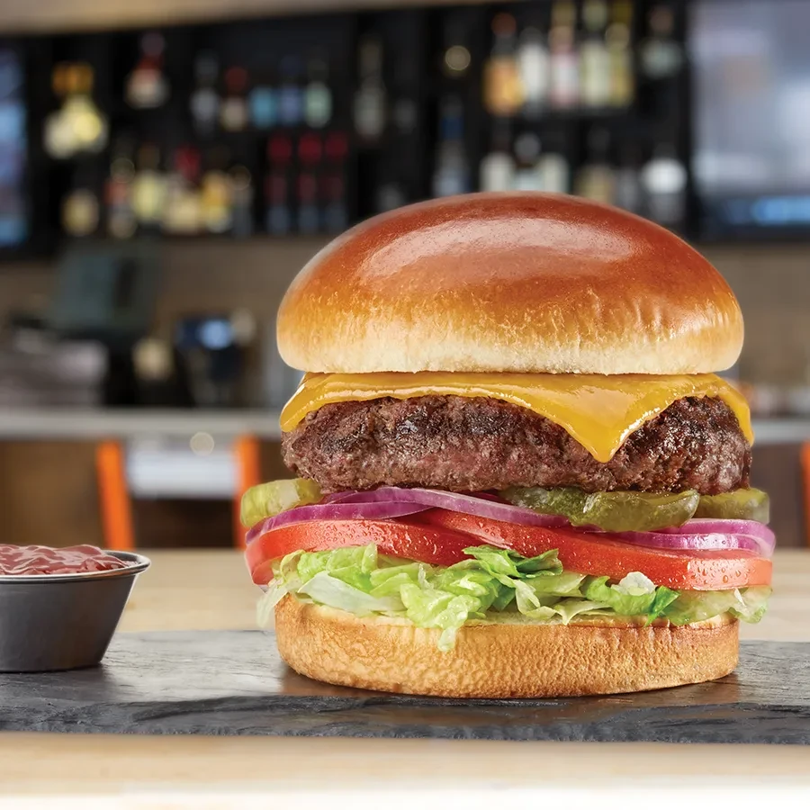 A cheeseburger with toppings and ketchup, in a restaurant setting.