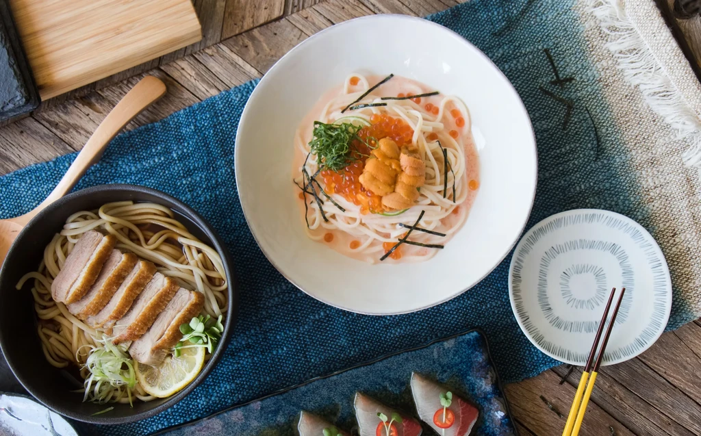 Overhead shot of Japanese dishes including noodles with duck and uni.
