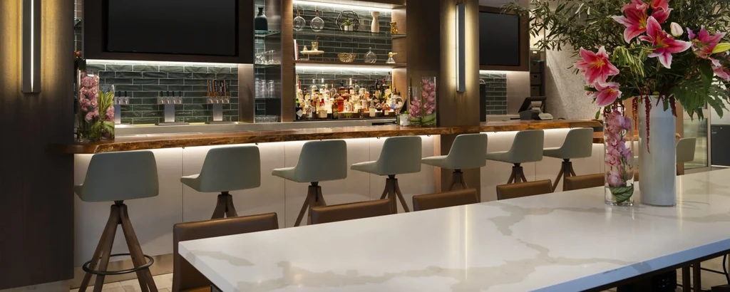 A modern, dimly lit bar with barstools and a long white table.