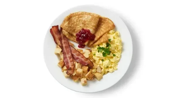 Plate of scrambled eggs, bacon, fried potatoes, and pancakes with jam.
