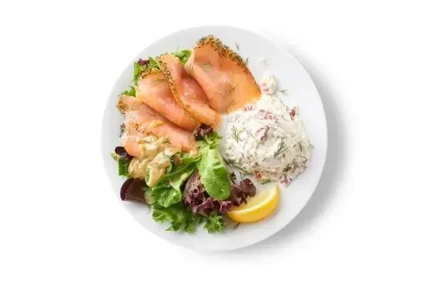 Smoked salmon with dill, potato salad, lettuce, and lemon wedge.
