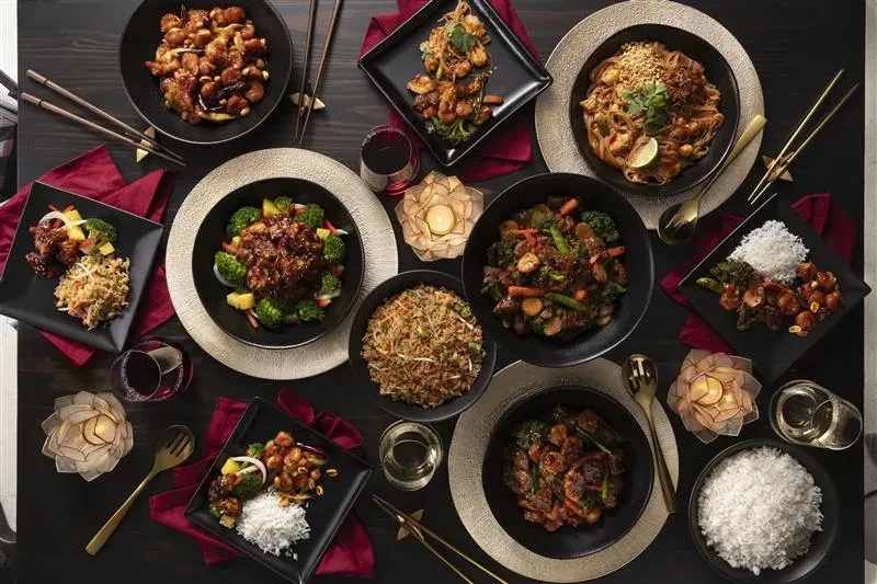 Elegant overhead view of a dining table laden with Asian dishes.