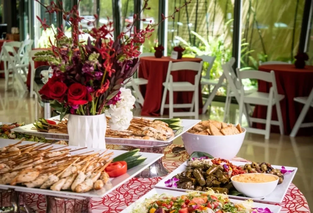 A large buffet with red and white flowers and a patio view.