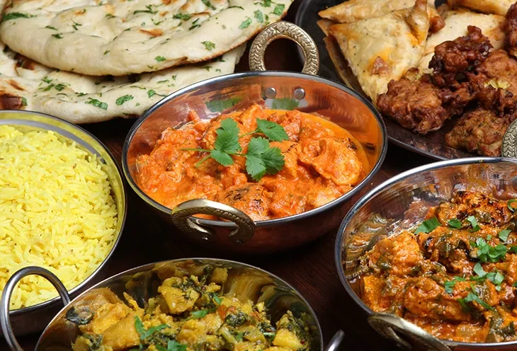 Various Indian dishes, including curries, naan, rice, samosas, and pakoras.
