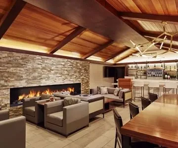 A hotel lounge with a long fireplace, bar, and wooden ceiling.