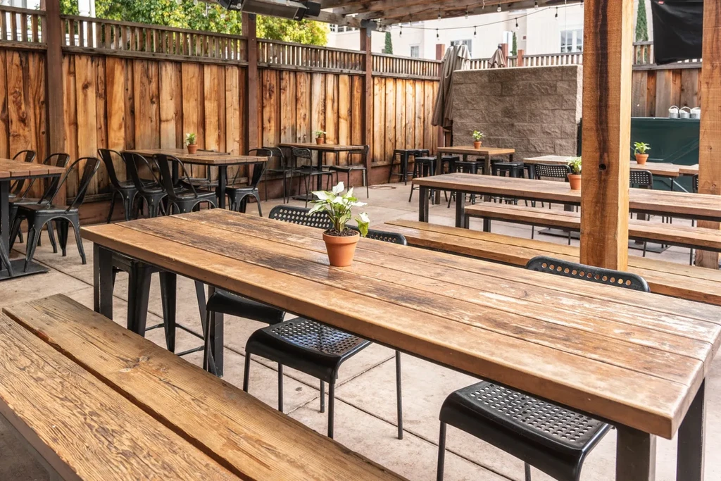 An outdoor patio dining area with wooden tables, benches, and chairs.