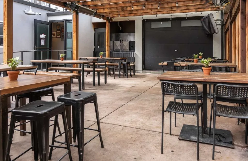 An empty outdoor patio with wooden tables and black metal chairs.