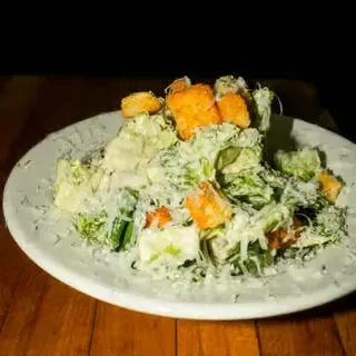 Caesar salad with croutons and grated cheese on a wooden table.