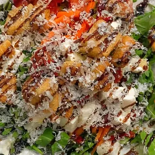 Overhead view: green salad with crispy pieces, grated cheese, and balsamic.