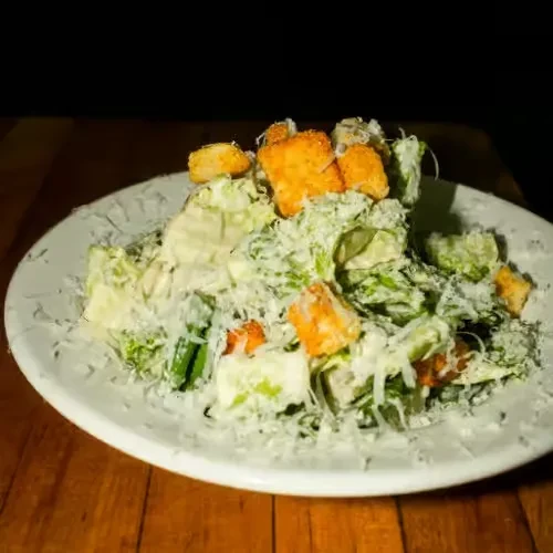 Close-up Caesar salad with lettuce, Parmesan, croutons, and creamy dressing.