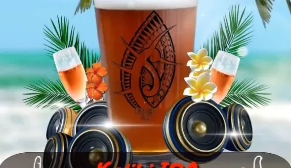 A pint glass with Hawaiian design, flowers, champagne, speakers on a beach.
