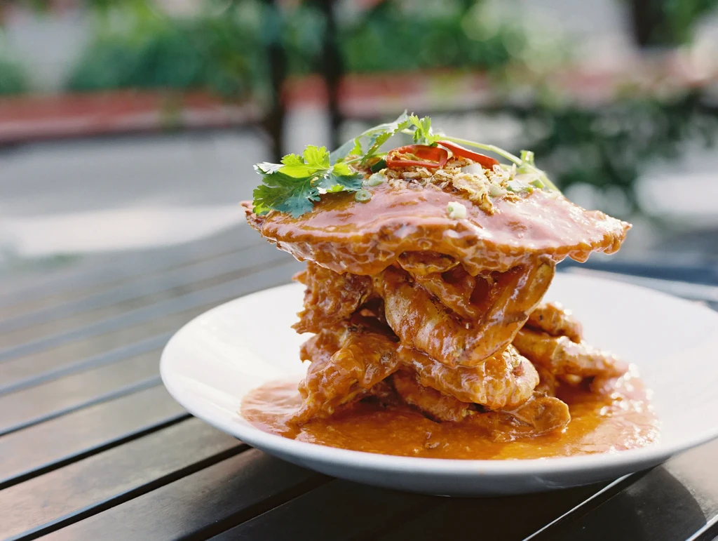 A plate of Chili Crab with cilantro on a wooden table.