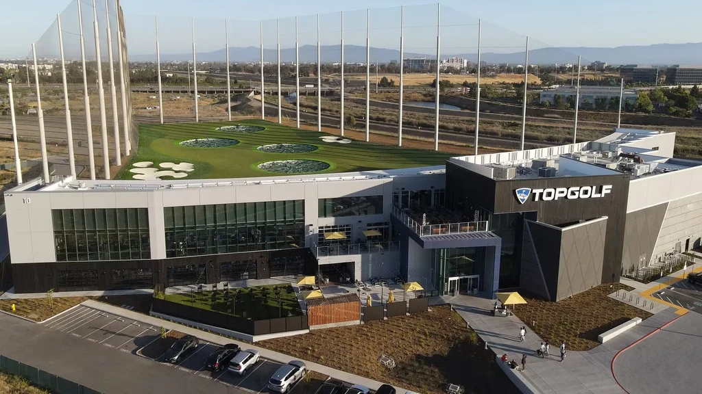 Aerial view of Topgolf facility, multi-story building, and driving range.