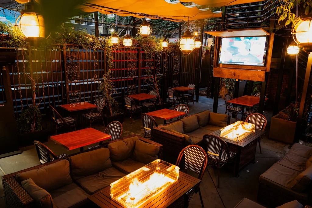 Outdoor patio restaurant with scattered tables and sofas under warm lights.