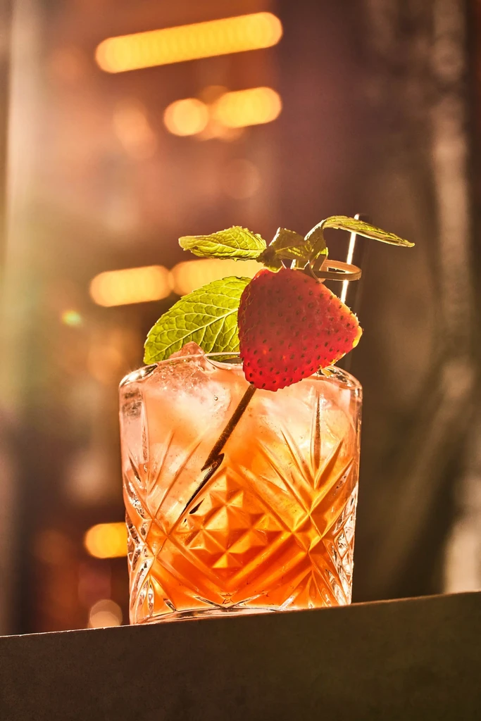 A cocktail with a strawberry and mint in a cut glass.
