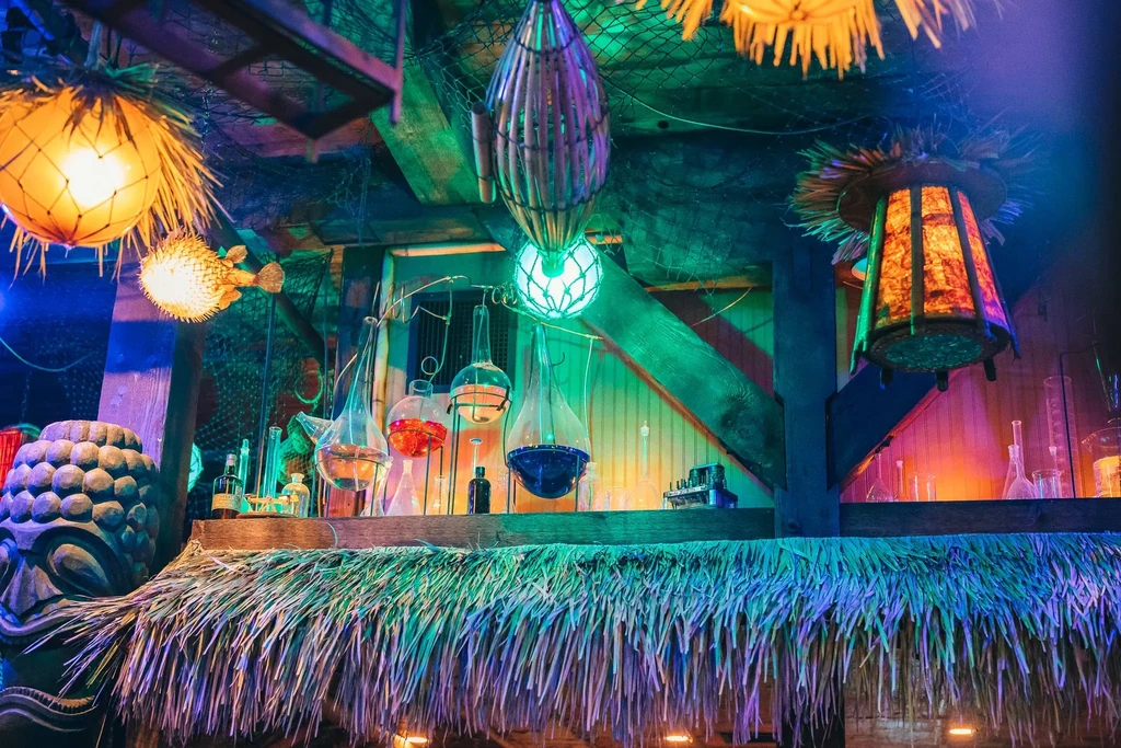 Tiki bar with glowing lanterns, glass beakers, and colorful liquid.