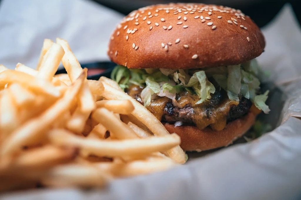 A close-up of a cheeseburger with shredded lettuce and a side of fries.