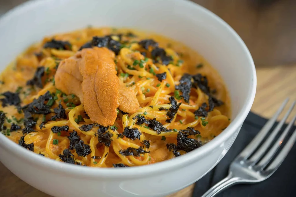 Uni pasta with seaweed and chives in a white bowl.
