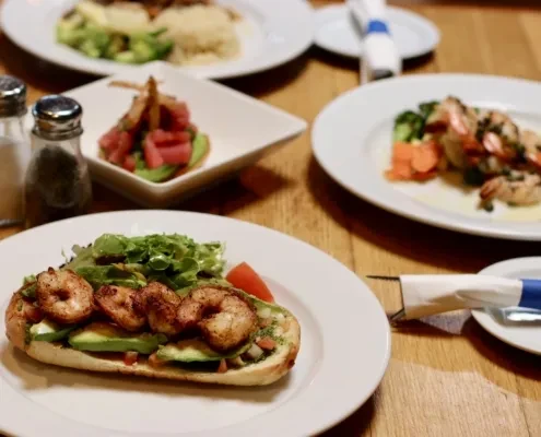 A dining table with several plates of shrimp and avocado dishes.