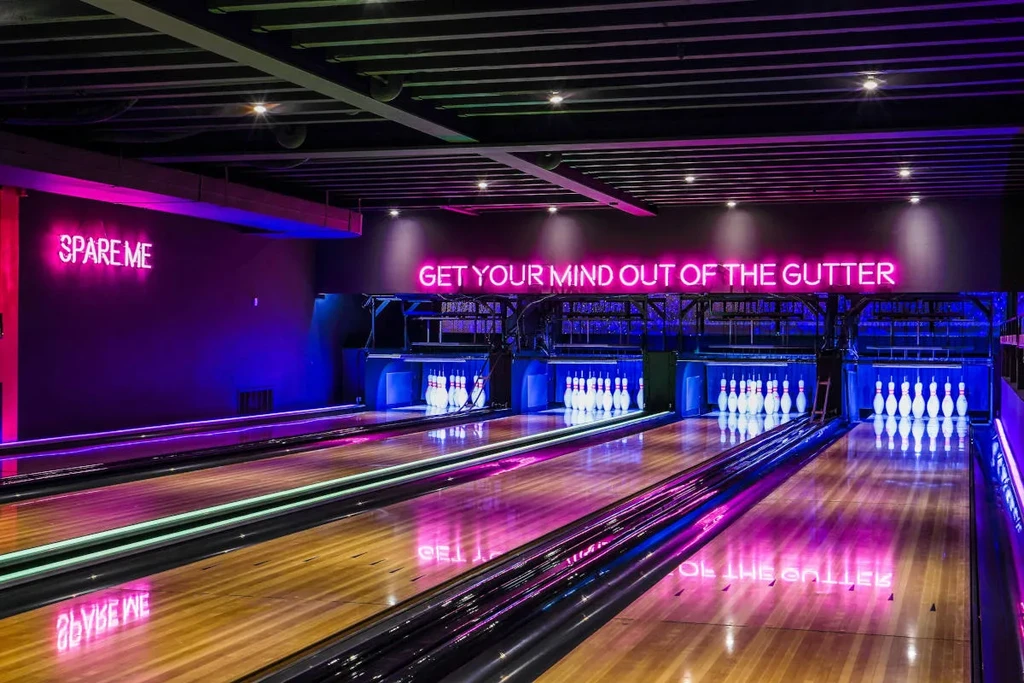 Bowling alley with neon signs, "SPARE ME" and "GET YOUR MIND OUT OF THE GUTTER."