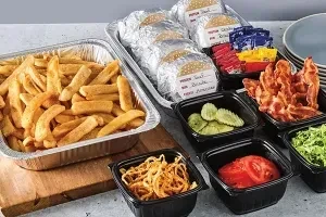 Build-your-own burger kit with fries, labeled patties, toppings, and condiments.