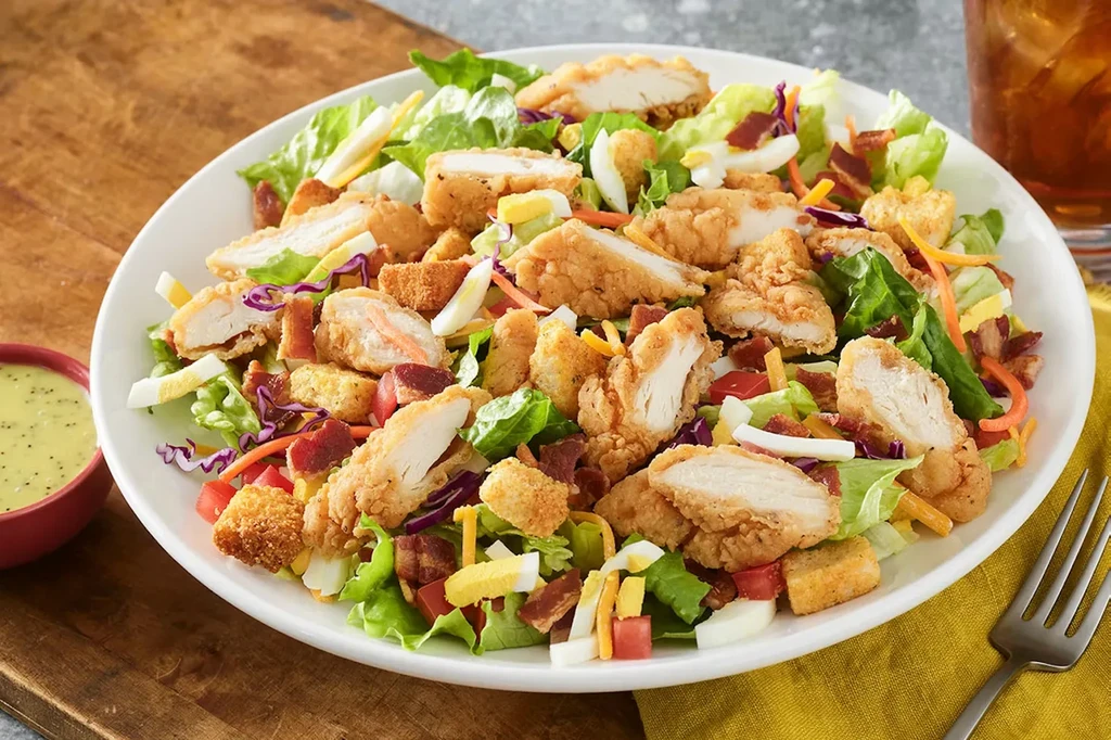 Large fried chicken salad, bacon, croutons, vegetables, and dressing.