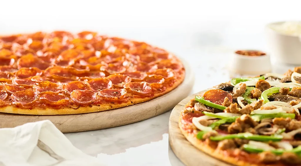 Sharply focused pepperoni pizza and a multi-topped pizza on wooden boards.