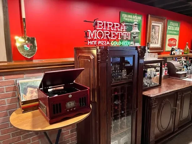 A retro Italian-themed bar interior with red walls and wooden furnishings.