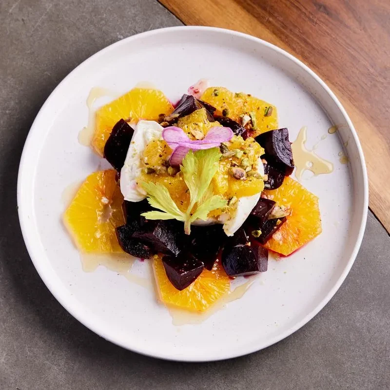 Orange and beet salad with cheese, pistachios, and honey.