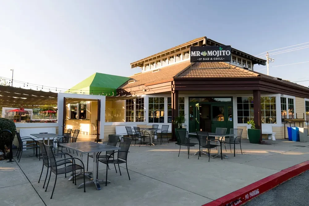 Restaurant exterior with patio seating and a green roof.