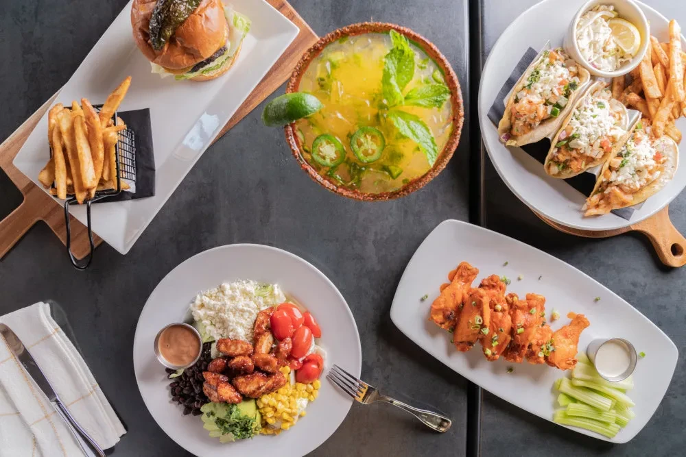Overhead view of various dishes and a drink on a dark table.