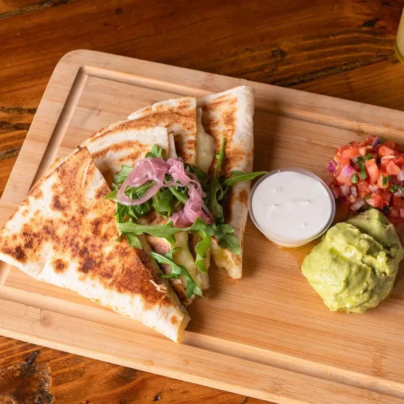 Cheese quesadilla with arugula, pickled onions, sour cream, salsa, and guacamole.
