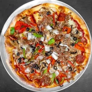 Whole pizza on a metal pan with various toppings, viewed from above.