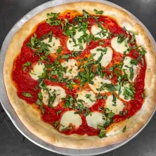A Margherita pizza on a round metal tray, topped with fresh basil.