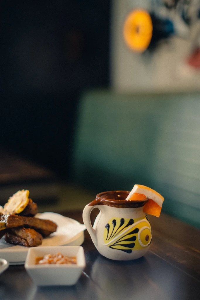 A decorated clay mug with an orange slice, next to small plates of food.